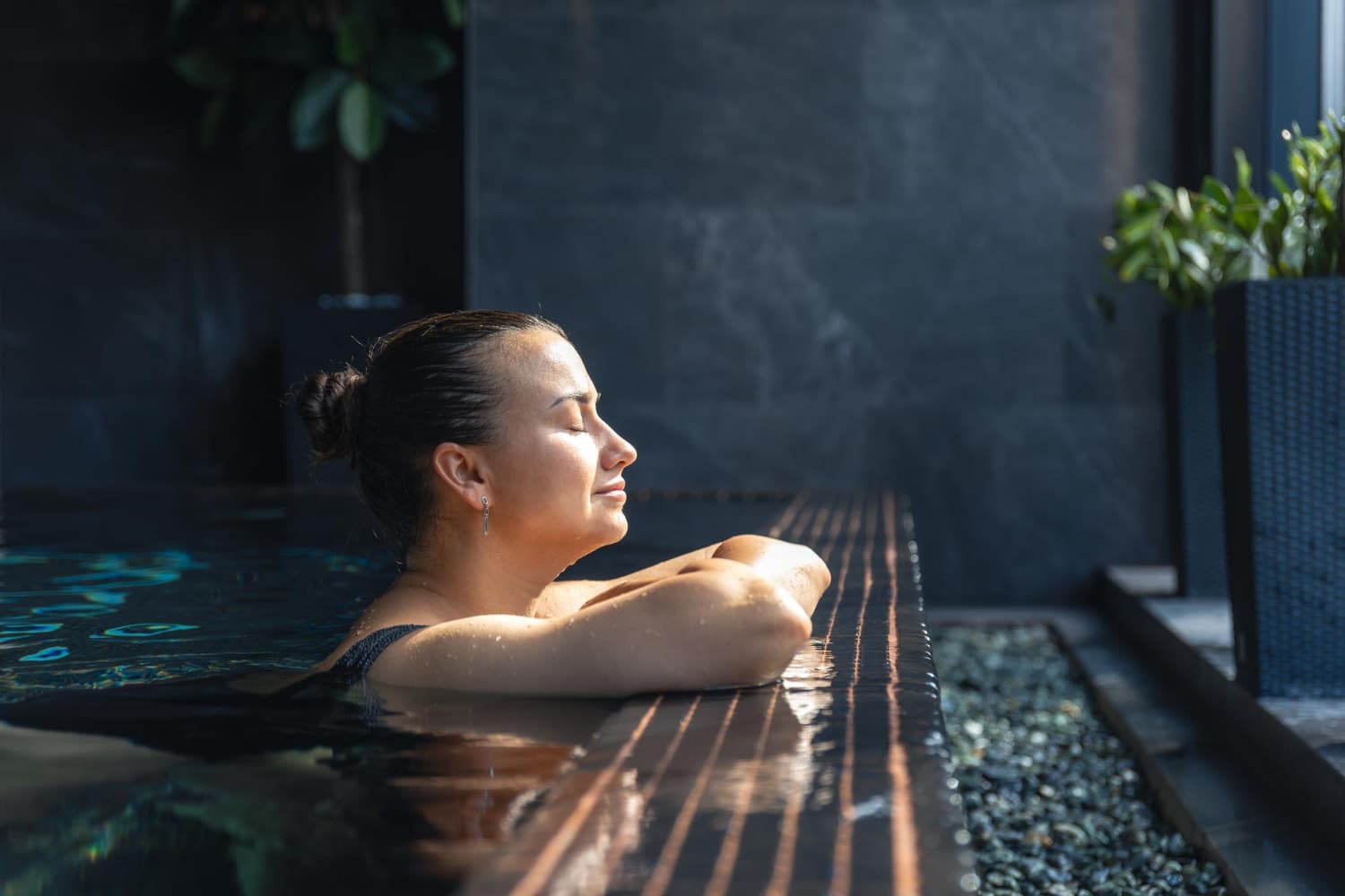 Femme se détendant dans un bassin thermal près de la fenêtre, pause méditative et silencieuse